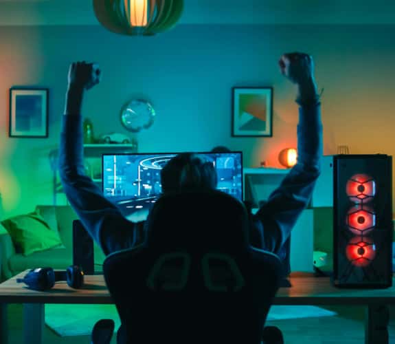 Ragazzo esultante di spalle mentre gioca a un video game in una stanza illuminata con vari colori